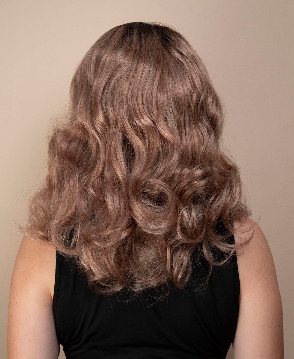 Woman with long, wavy, brown hair against a beige background