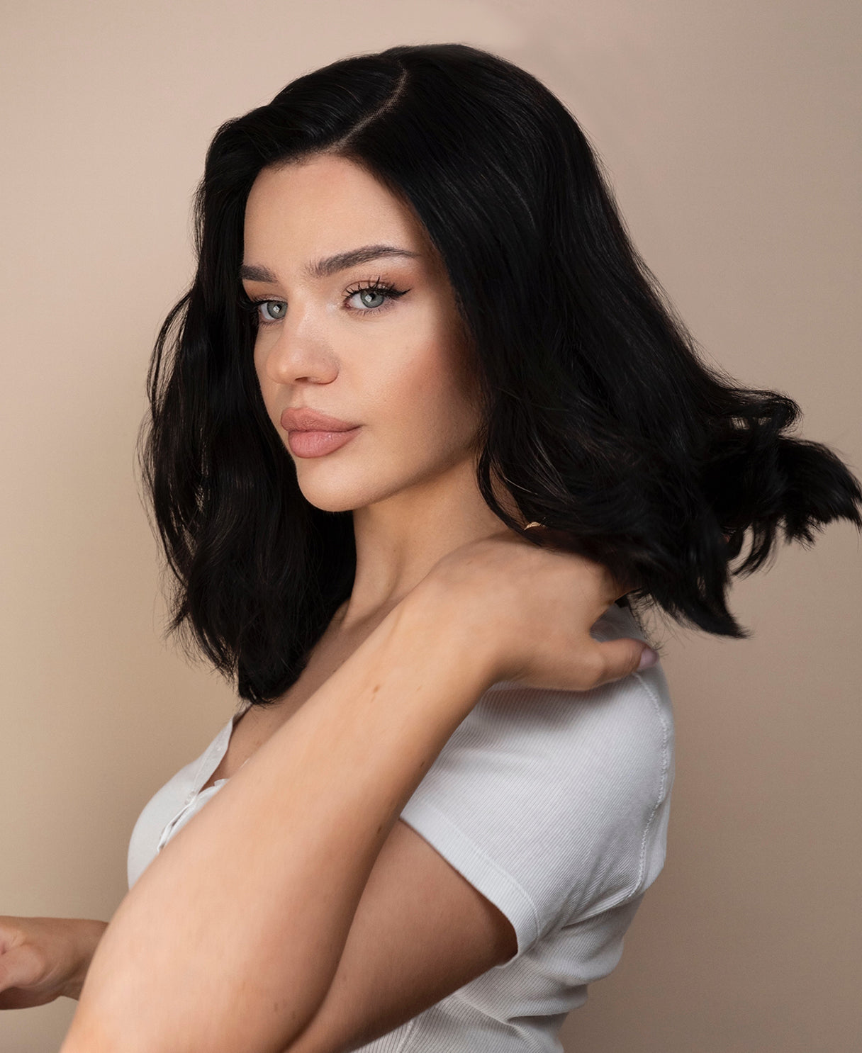 Woman with styled black hair against a beige background