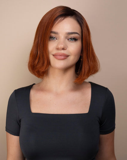 Woman with red hair wig wearing a gray top against a beige background