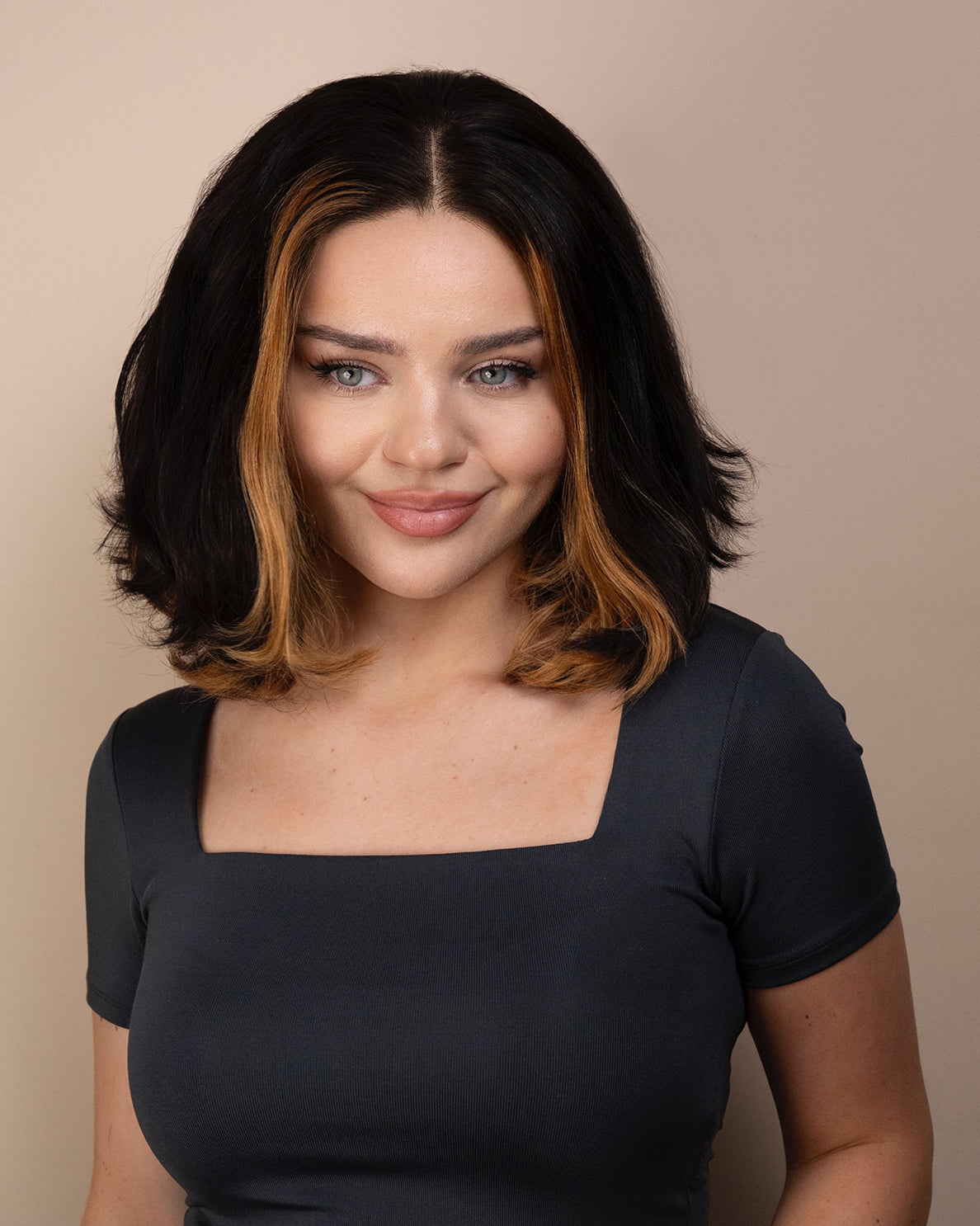 Woman with bob human hair wig and a gray top against a beige background
