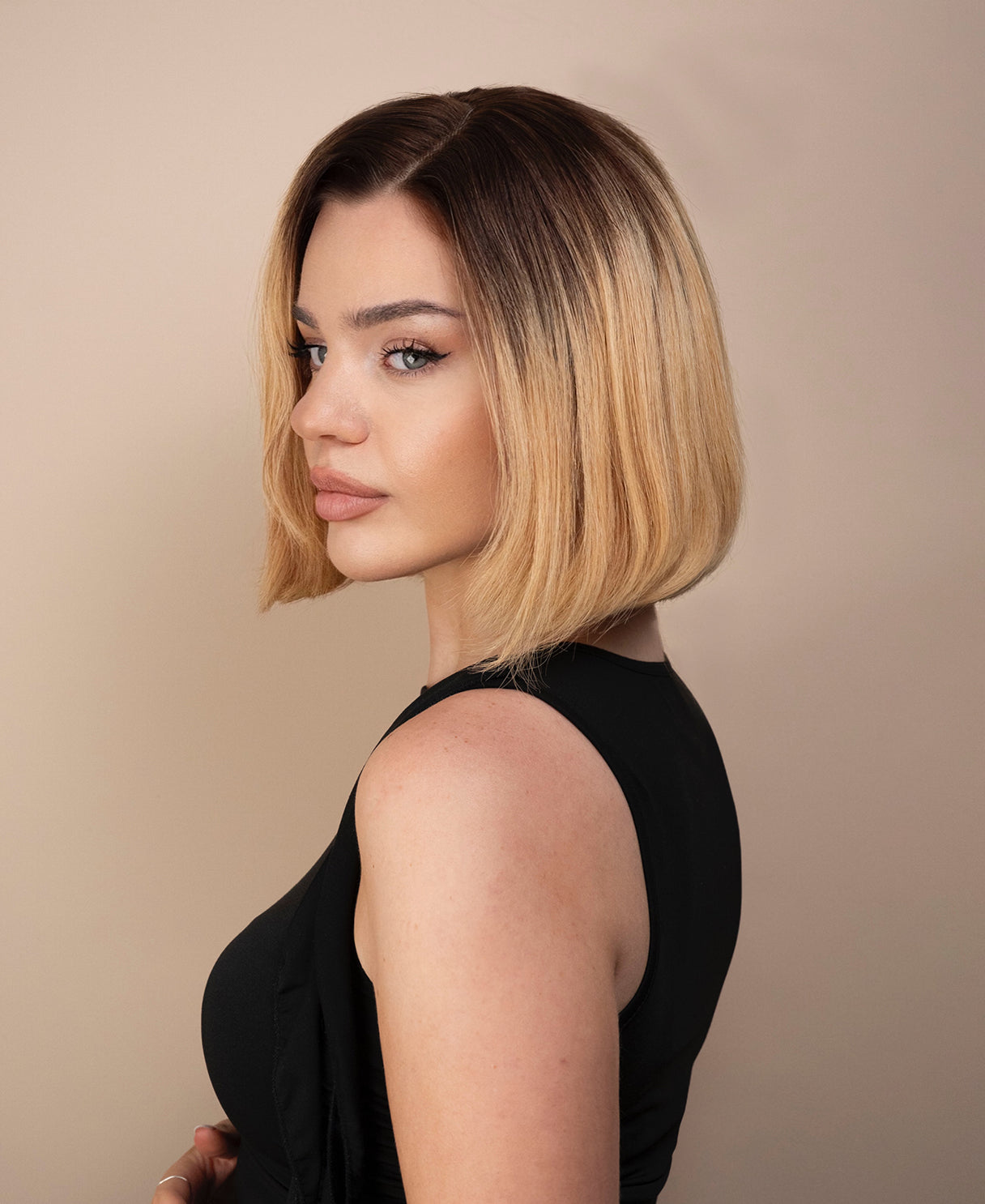 Woman with a stylish haircut bob wig against a beige background