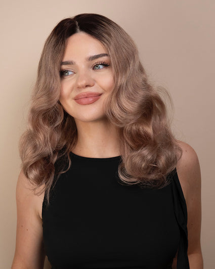 Woman with wavy ash wig wearing a black top against a beige background