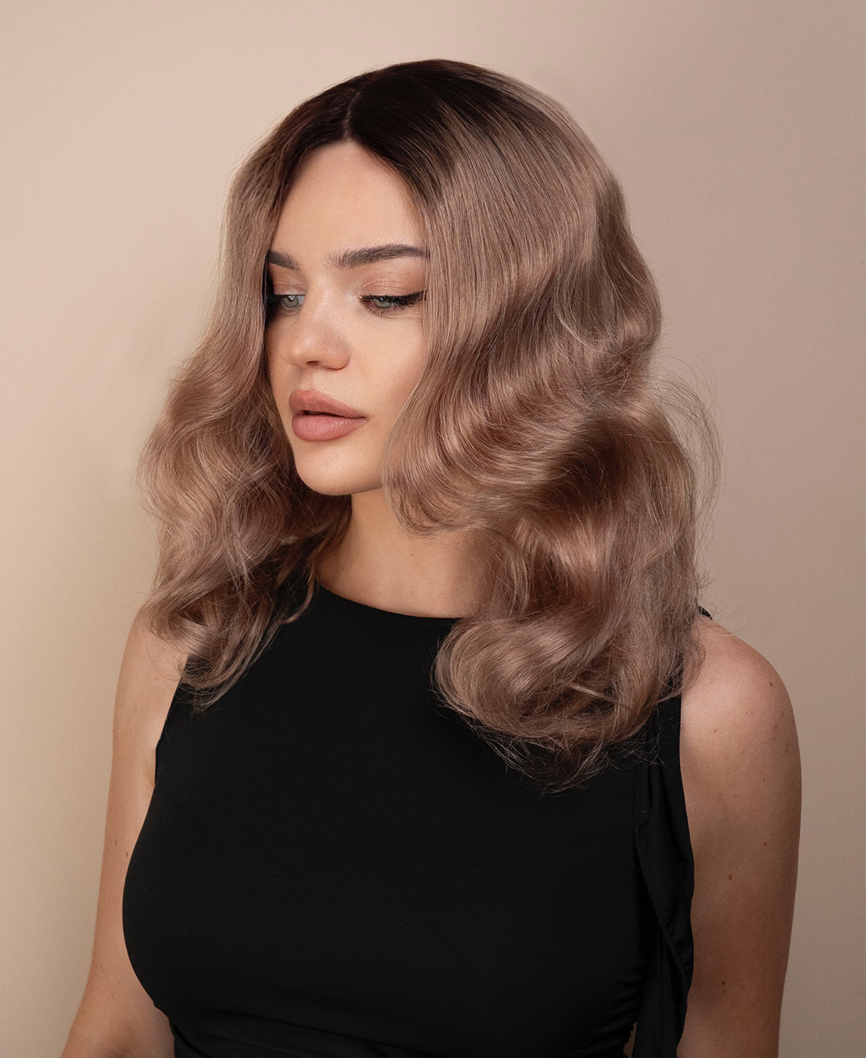Woman with wavy ash wig wearing a black top against a beige background
