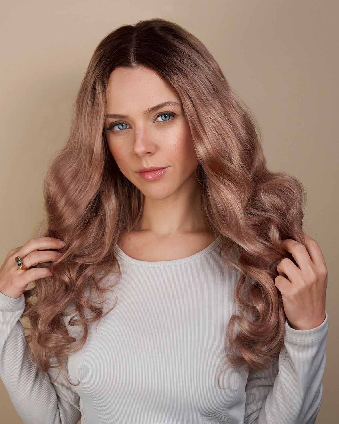 Woman with long, wavy, pinkish-brown hair against a beige background