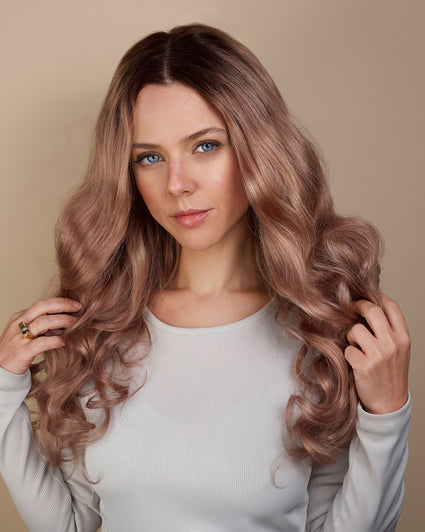 Woman with long, wavy, pinkish-brown hair against a beige background