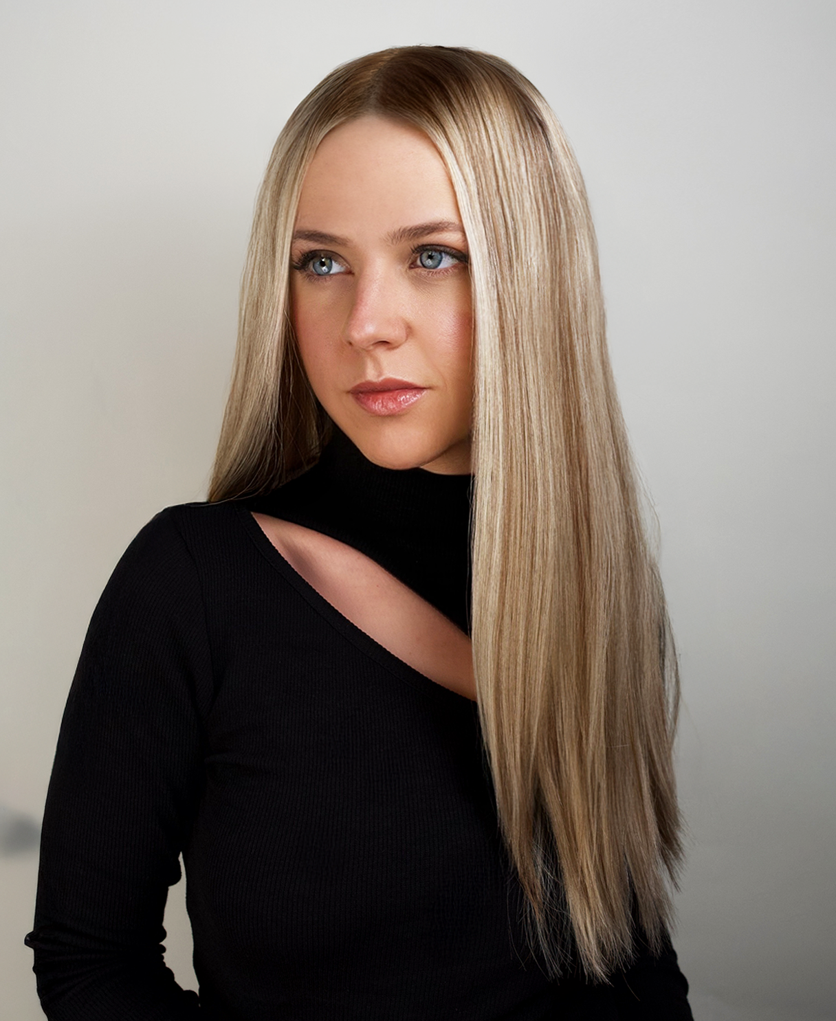 Woman with long blonde hair wig wearing a black top against a neutral background