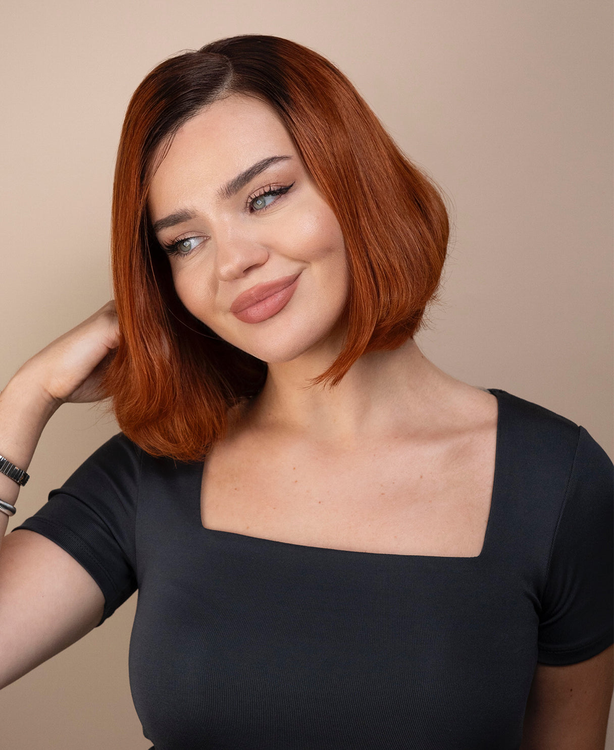 Woman with red hair wig wearing a gray top against a beige background