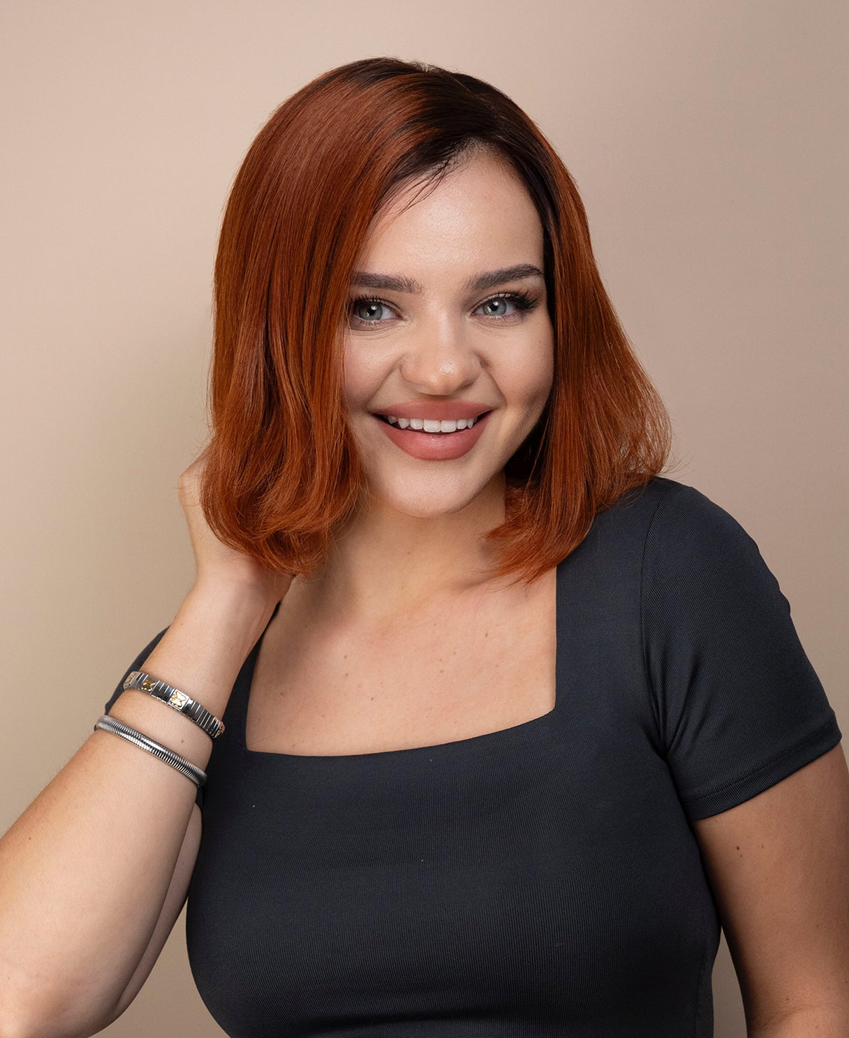 Woman with red hair wig wearing a gray top against a beige background