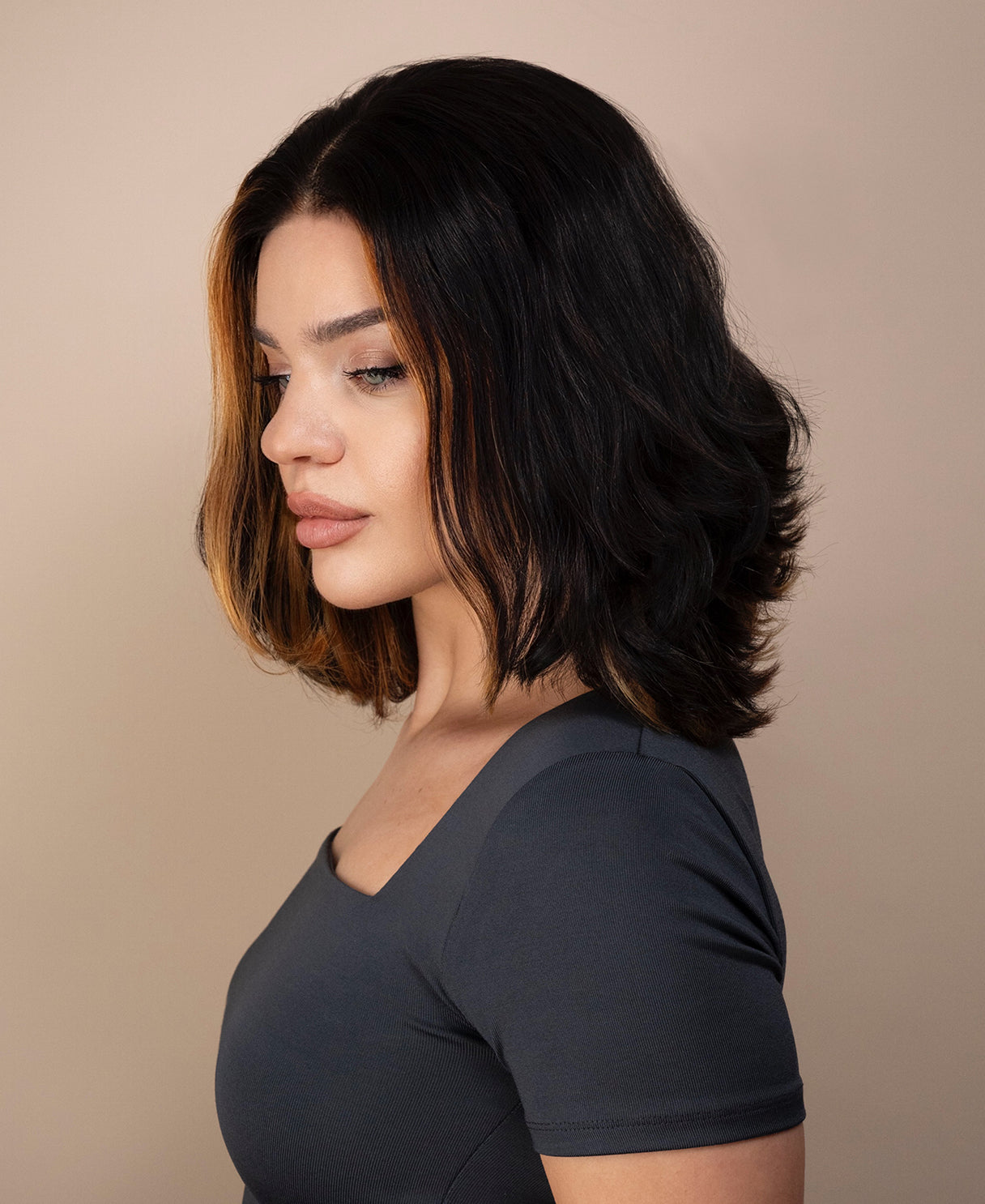 Woman with bob human hair wig and a gray top against a beige background