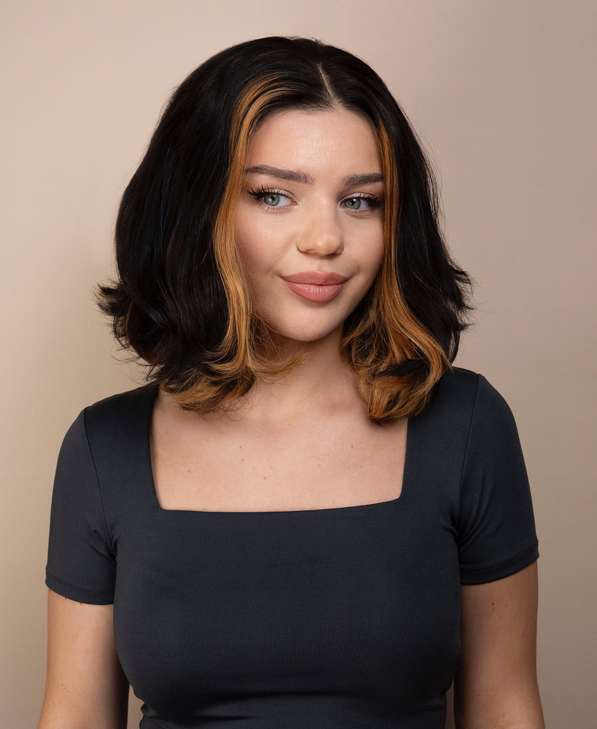 Woman with bob human hair wig and a gray top against a beige background