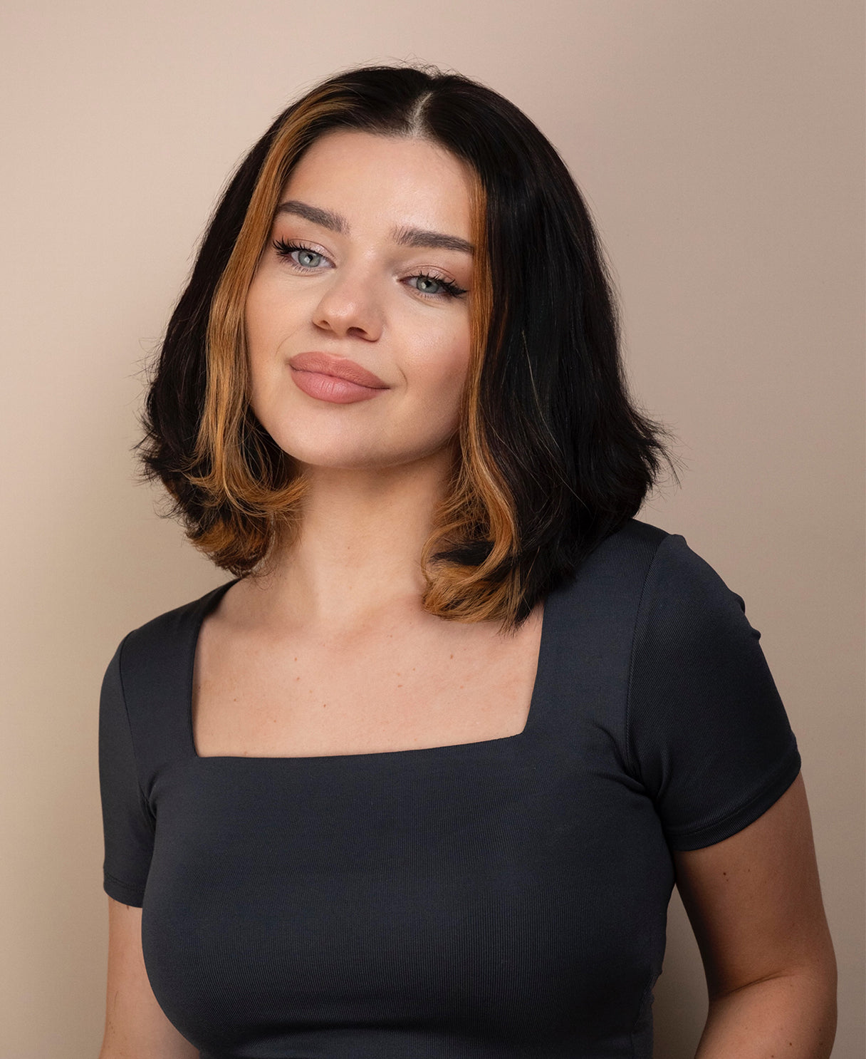 Woman with bob human hair wig and a gray top against a beige background