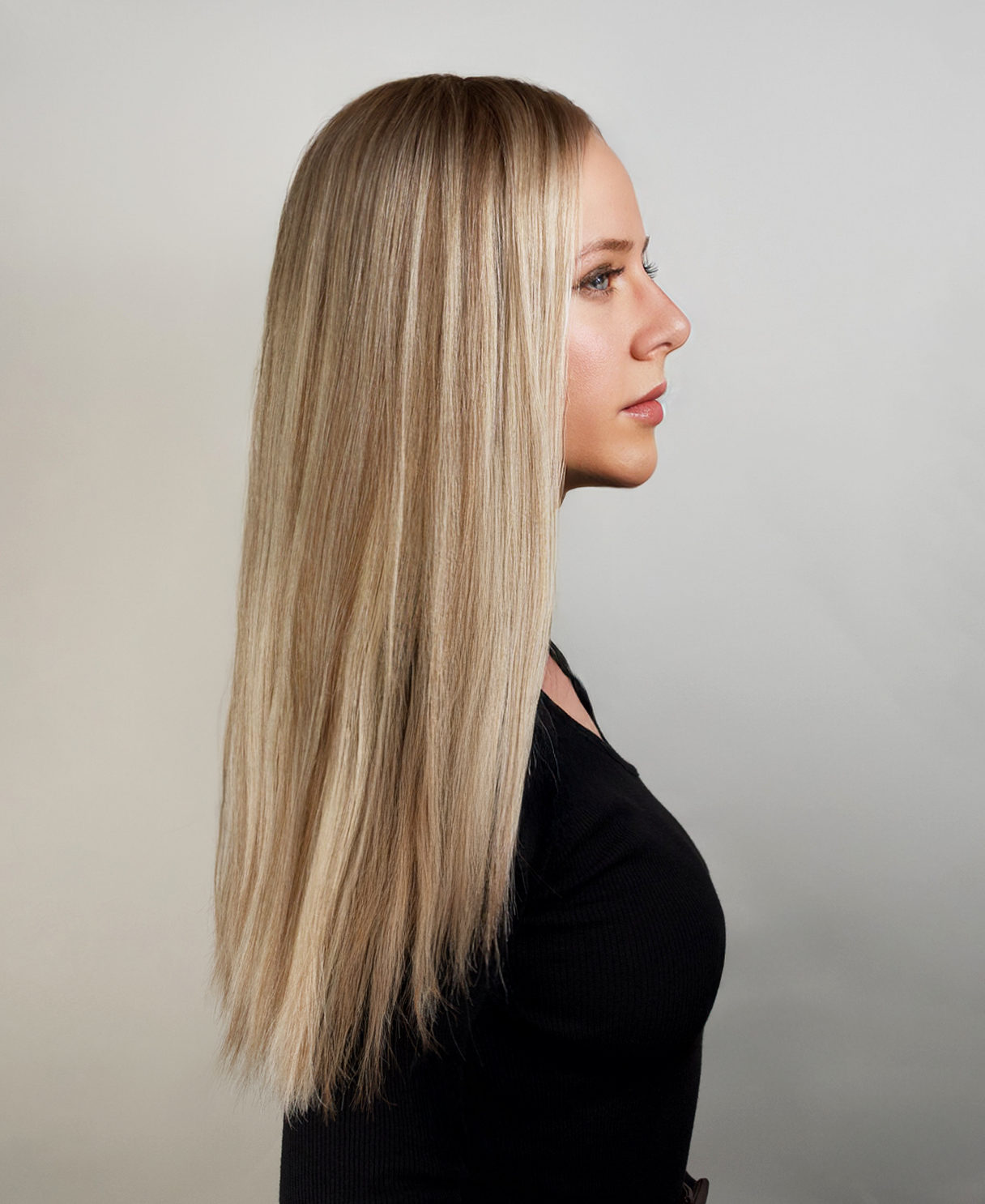 Woman with long, straight blonde hair wig against a neutral background